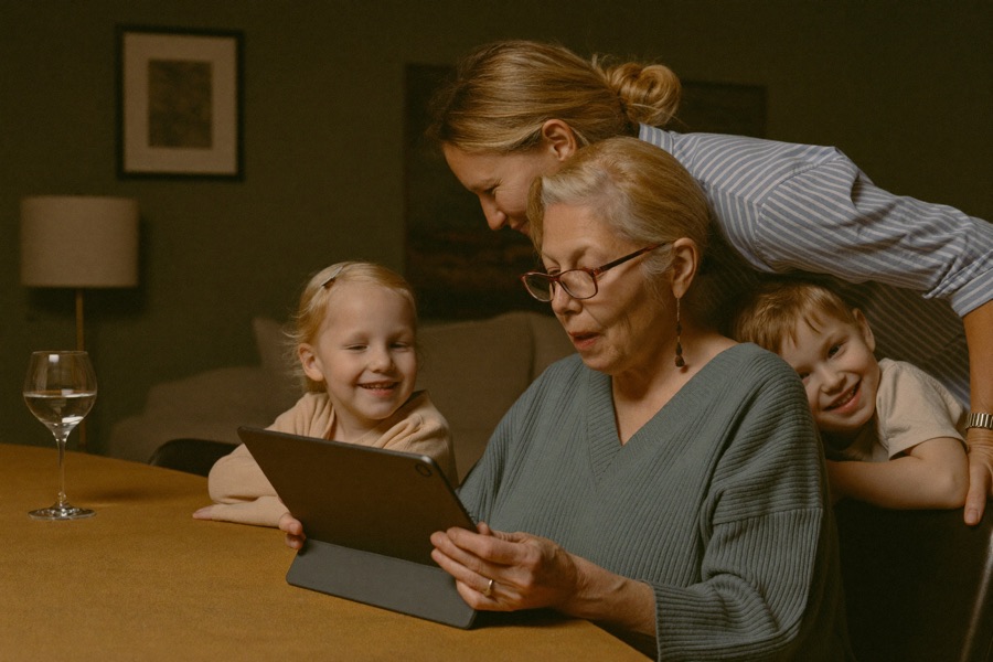 Großmutter zeigt Tochter und Enkelkind stolz etwas auf dem Tablet